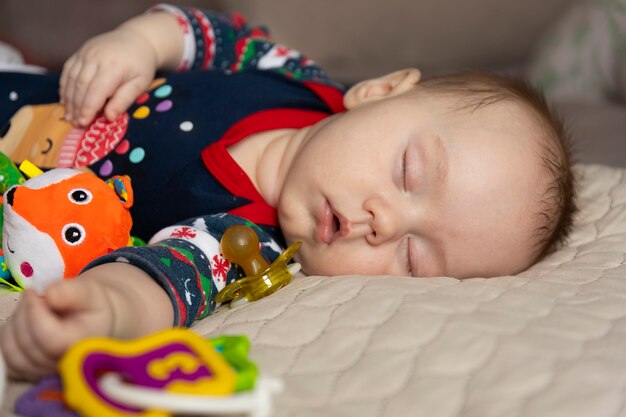 Bebê fofo dormindo, três meses de idade, com brinquedos. Foco seletivo.