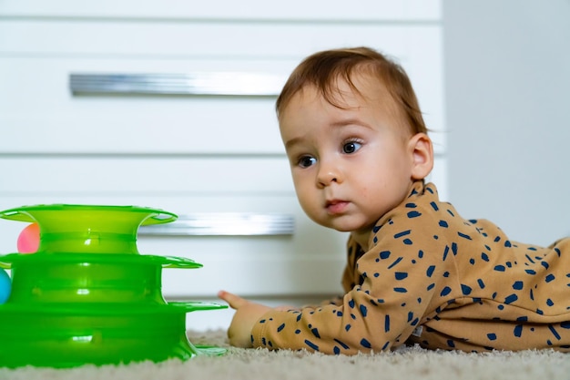 Bebê fofo e alegre brincando com brinquedos coloridos em casa Brinquedos para crianças pequenas Interior para berçário de menino