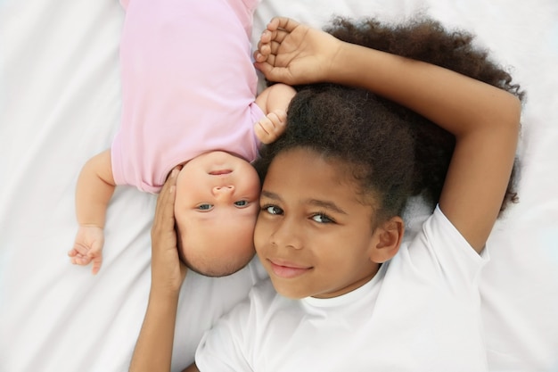 Bebê fofo e irmã mais velha na cama