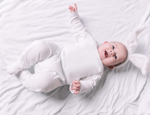 Bebê fofo e sorridente deitado na cama