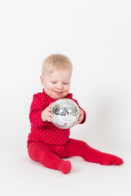 Bebê fofo em roupa vermelha brincando com uma bola de festa