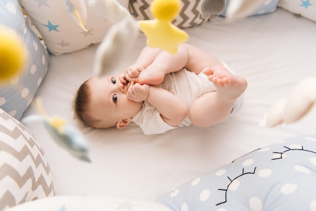 Bebê fofo encontra-se em uma cama redonda branca. Creche leve para crianças pequenas.