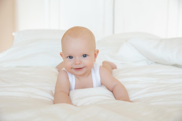 Bebê fofo está deitado na cama no quarto sorrindo