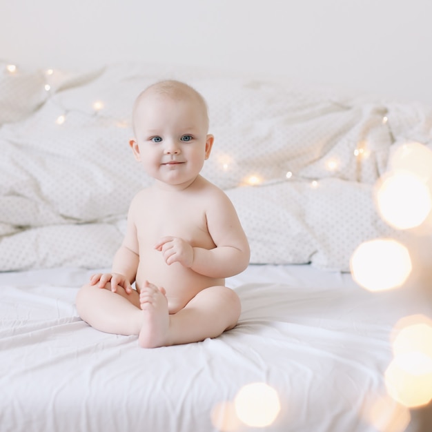 Bebê fofo feliz e sorridente sentado na cama