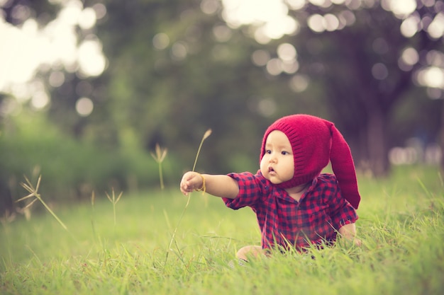 Bebê fofo feliz em um campo jogando com picos naturais ao pôr do sol de verão