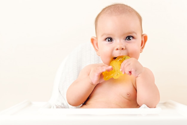 Foto bebê fofo infantil criança mordendo sentado cadeira alta mastigando amarelo eething brinquedo cópia espaço brilhante