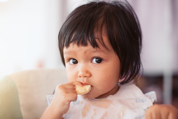 Bebê fofo menina criança asiática comendo comida saudável sozinha