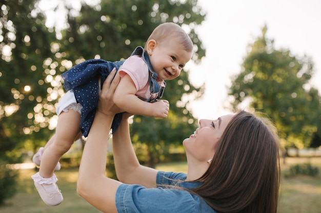 Bebê fofo nas mãos da mãe do lado de fora Família no parque no verão Estilo jeans Mãe e filha em jeans