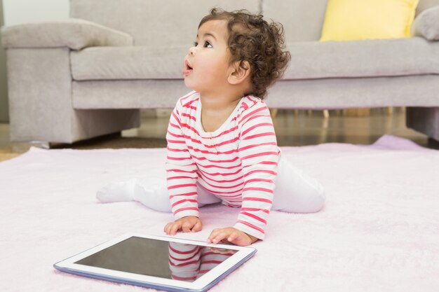 Foto bebê fofo no tapete com tablet em casa