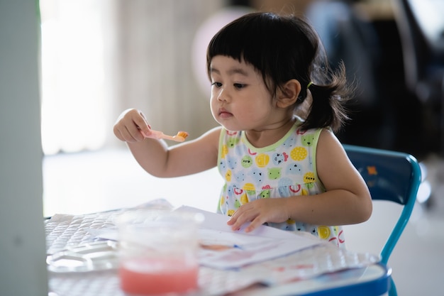 Bebê fofo pintando fantoche de gesso na mesa, conceito de arte