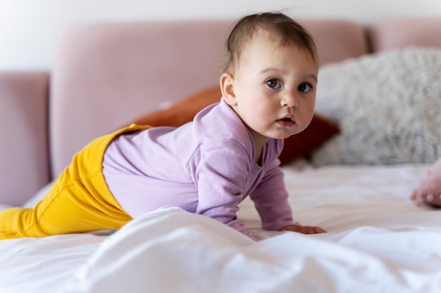 Bebê fofo rastejando na cama e parecendo surpreso