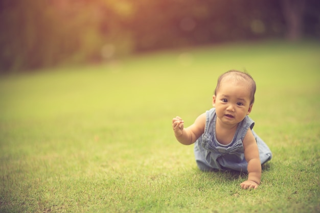 Bebê fofo rastejando na grama. Cor vintage