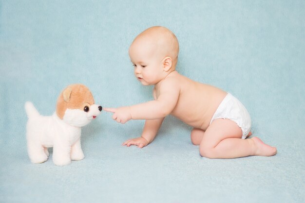 Bebê fofo tocando o nariz de um cachorro de brinquedo