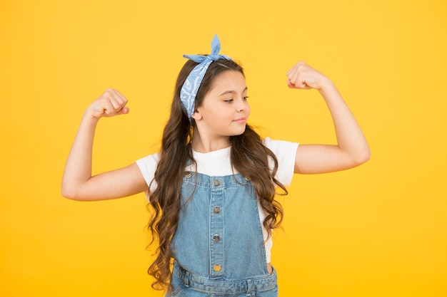 Bebê forte. Tendência da moda. Férias de verão. Nó de bandana de cabelo longo encaracolado de menina. Pequena fashionista. Infância feliz. Roupas adolescentes modernas. Garota de moda criança pequena bonitinha. Acessórios fashions. Poder.