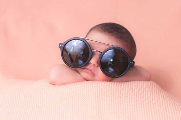 Foto un bebé con gafas de sol y una manta rosa.