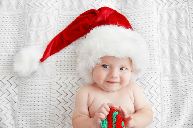 Bebé con gorro de Navidad en la cama blanca