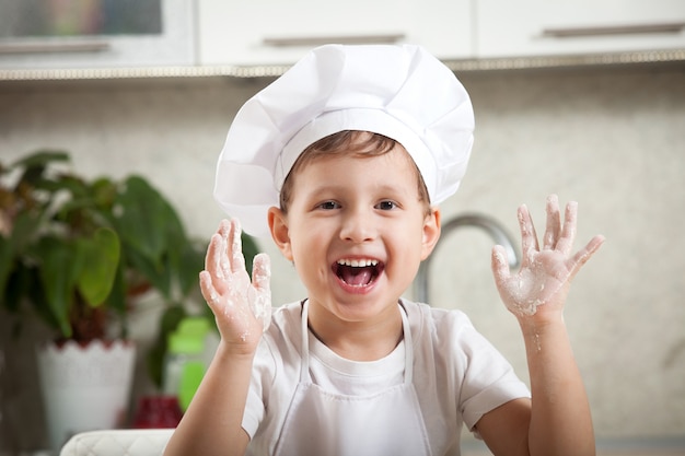 Bebé gracioso con harina, feliz niño emocional sonríe feliz