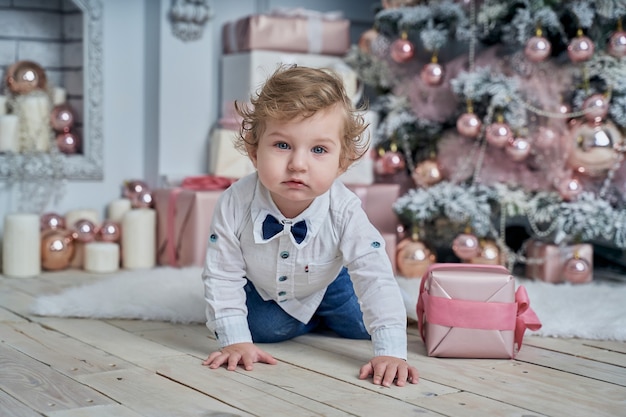 Bebé gracioso junto al árbol de Navidad.