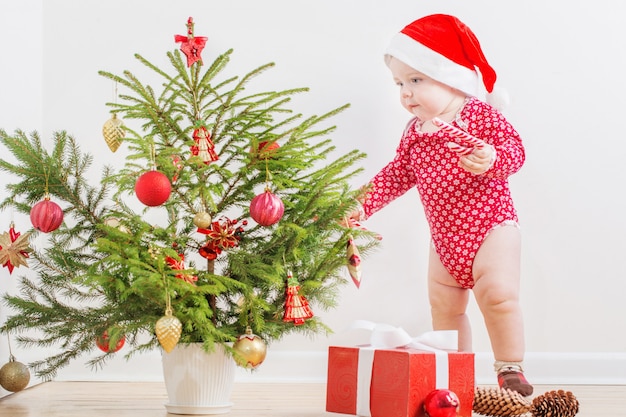Bebé gracioso con pequeño abeto de Navidad en casa