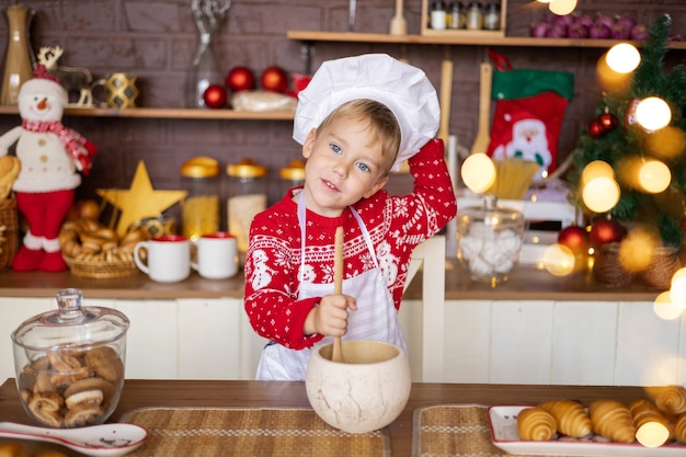 Bebé hornear galletas navideñas en una acogedora cocina en casa concepto de vacaciones feliz navidad y año nuevo