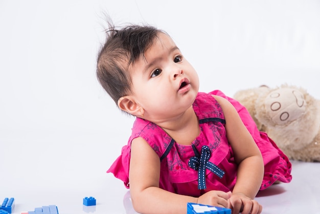 Bebê indiano brincando com brinquedos ou blocos, criança asiática brincando com brinquedos no fundo branco, bebê indiana brincando com brinquedos, criança indiana brincando com brinquedos enquanto estava deitada no chão