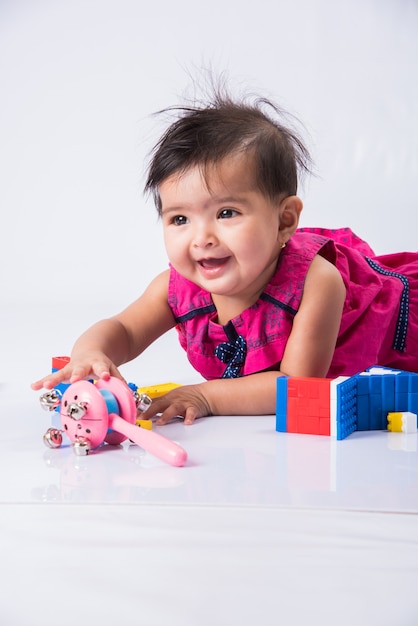 Bebê indiano brincando com brinquedos ou blocos, criança asiática brincando com brinquedos no fundo branco, bebê indiana brincando com brinquedos, criança indiana brincando com brinquedos enquanto estava deitada no chão