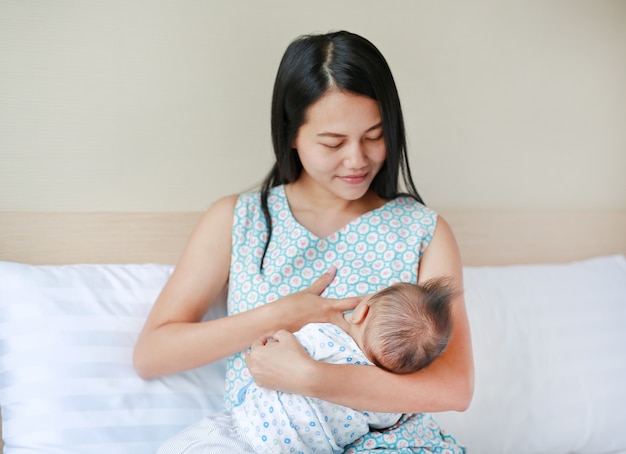 Bebê infantil, alimentando-se de mãe amamentando seu filho recém-nascido na cama.