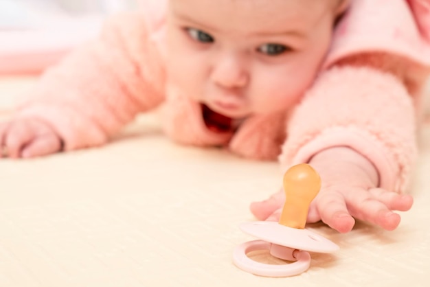 Foto bebê infantil tentando pegar chupeta.