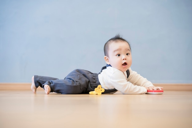 Bebé japonés arrastrándose por el suelo de madera de la habitación