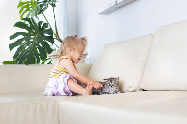 Bebé jugando con un gatito en el sofá