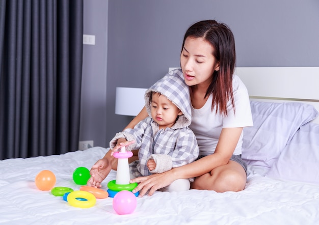 bebé jugando juguetes con la madre en la cama