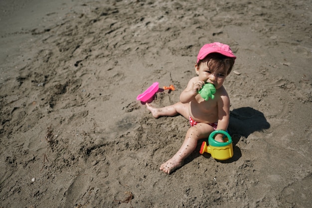 Un bebé jugando con juguetes de playa en la arena