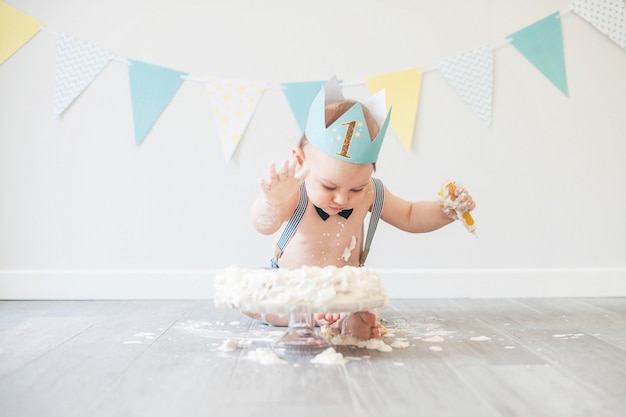 Bebé jugando con un pastel durante su fiesta de cumpleaños de pastel aplastante