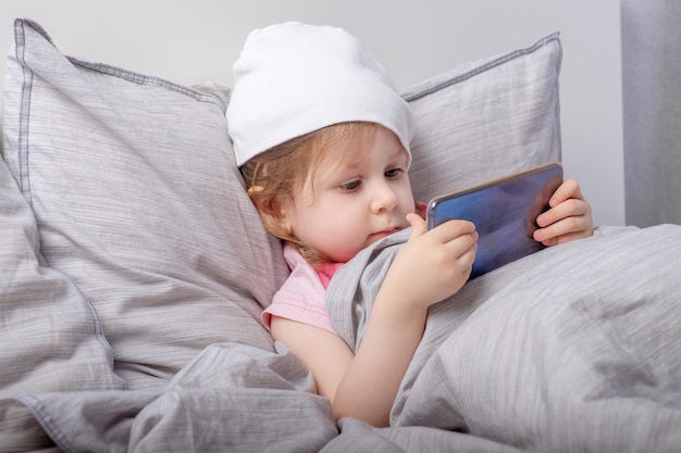 Bebé jugando en un teléfono inteligente en la cama