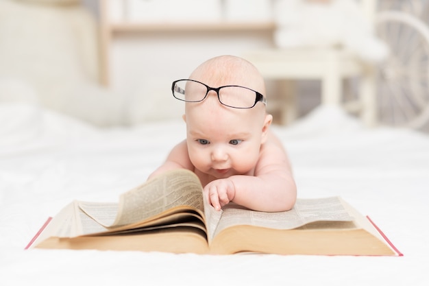 Bebê lendo um livro ou olhando para ele no berçário, conceito de aprendizagem e desenvolvimento