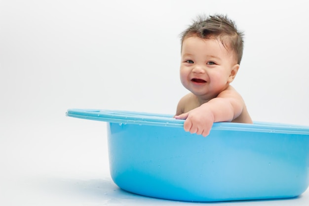 Un bebé lindo en la bañera contra un fondo blanco