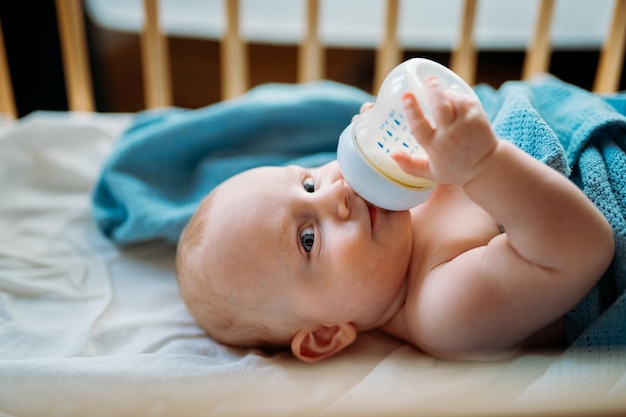Un bebé lindo bebiendo leche en la cuna