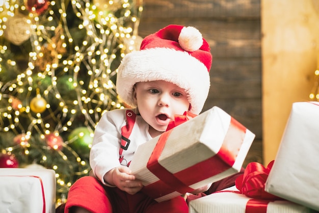 Bebé lindo divertido emocionado sorprendido cerca del árbol de navidad