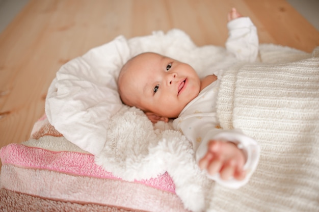 Bebé lindo en un dormitorio de luz blanca El bebé recién nacido es lindo. En ropa de cama para niños nacidos - imágenes