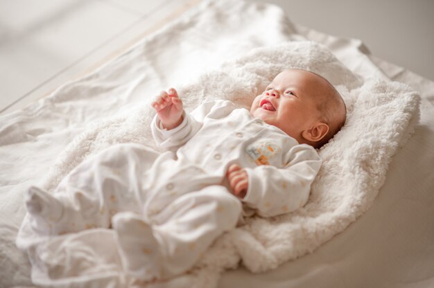 Bebé lindo en un dormitorio de luz blanca el bebé recién nacido es lindo. en ropa de cama para niños nacidos - imágenes