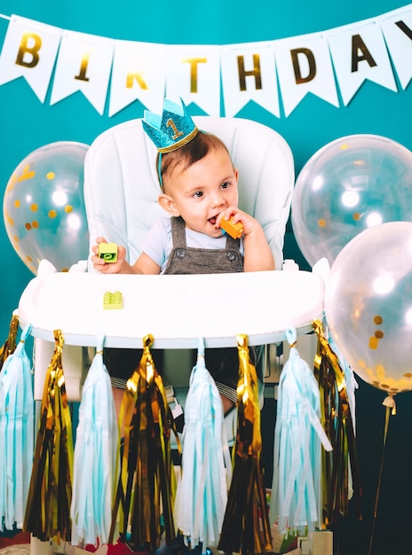 Un bebé lindo sentado en una silla alta en una fiesta de cumpleaños