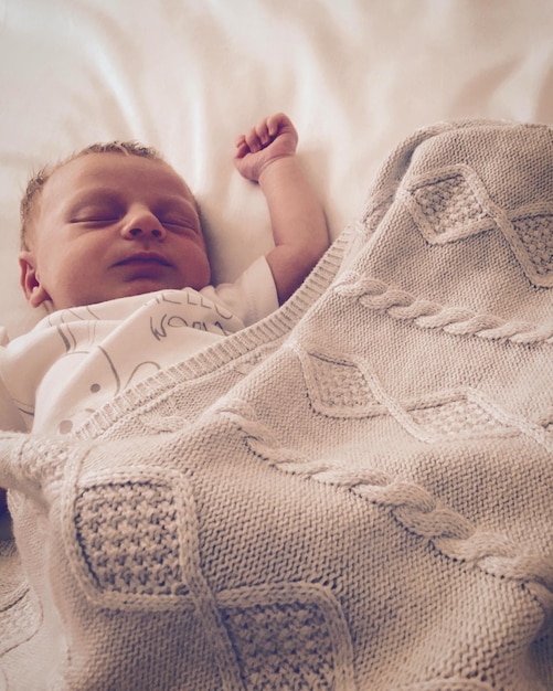 Foto bebê loira a dormir na cama.