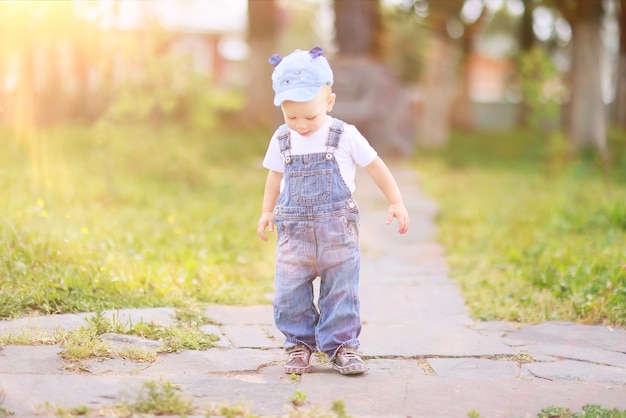 bebê macacão jeans menino caminha no verão