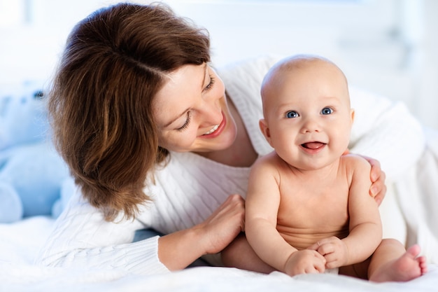 Foto bebé y madre en casa en la cama. mamá e hijo.