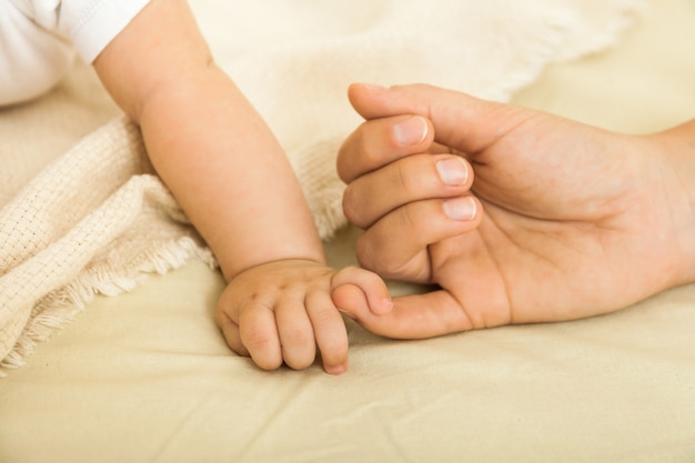 Bebé y las manos de las madres de cerca. Concepto de familia