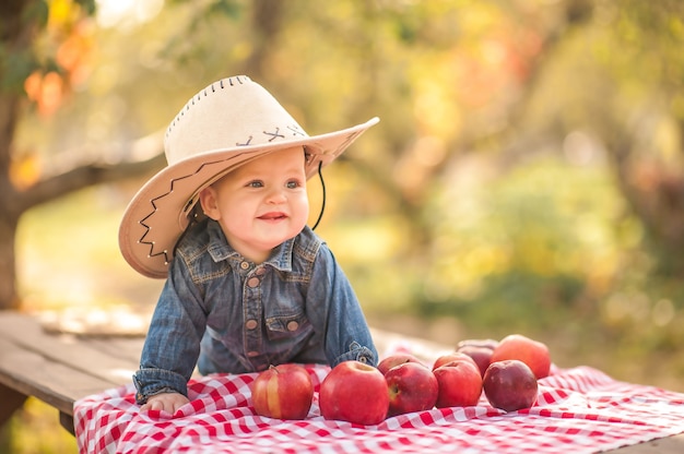 Bebé y manzanas en la naturaleza. Cosecha de manzanas y granjero de niño pequeño divertido