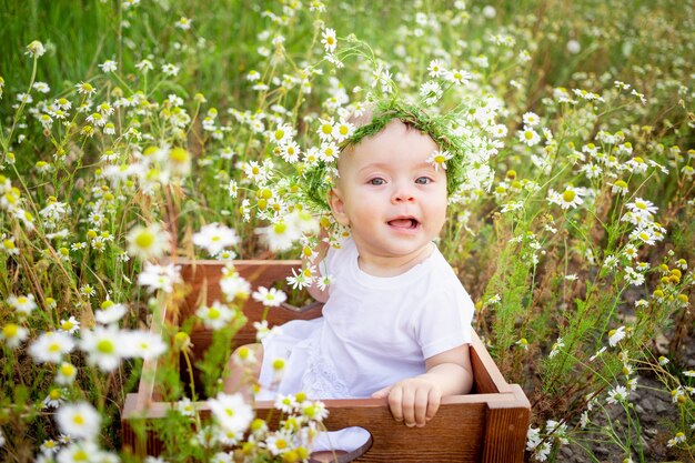 Bebé en margaritas, niña en una corona de margaritas en verano en el césped