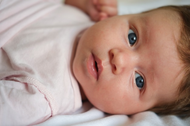 Bebé menina bonitinha com cabelo escuro deitado na manta branca. conceito de puericultura e maternidade. vida nova. Família feliz. Em casa. AME. Doce. Ternura.