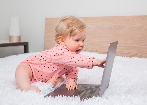 Bebê menina bonitinha com laptop no quarto dos pais