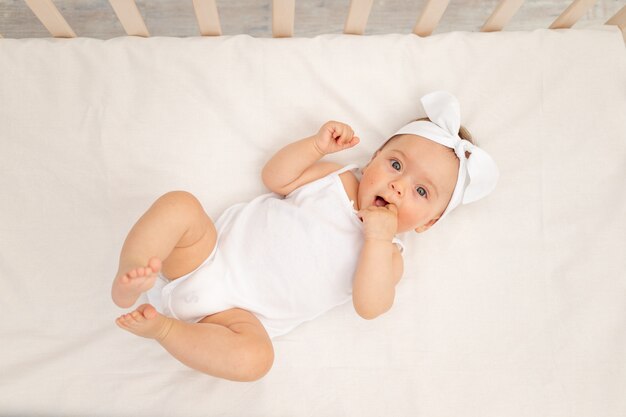 Bebê menina bonitinha sentada na cama